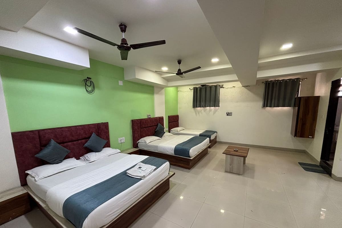 A hotel room with two beds, a ceiling fan, a small table, and a mirror.