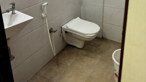 A small bathroom with a toilet, sink, and a mirror. - HOTEL VIVANTA (Ahmedabad)