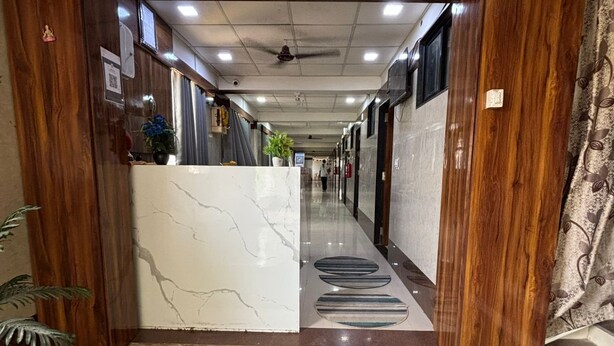 A hotel entrance with a reception desk, a ceiling fan, and a hallway leading to rooms. - HOTEL VIVANTA (Ahmedabad)