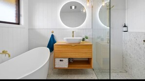 A modern bathroom with a freestanding bathtub, a round mirror, and a glass-enclosed shower. - Seabreeze Retreat by the Beach (Sulphur Creek)