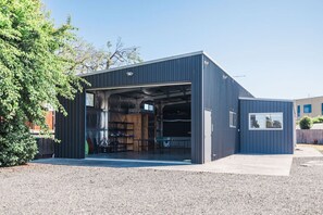 A modern building with a large open garage door, a wooden table inside, and a small window on the side. - The Family Beach Base, Port Sorell (Port Sorell)