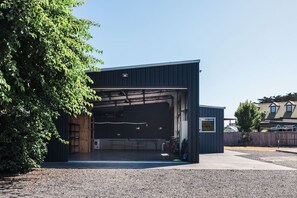 A modern building with a large garage door, a small attached structure, and a gravel driveway. - The Family Beach Base, Port Sorell (Port Sorell)