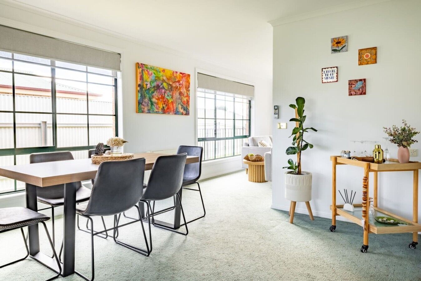 A modern office space with a long table, chairs, a potted plant, and artwork on the walls.