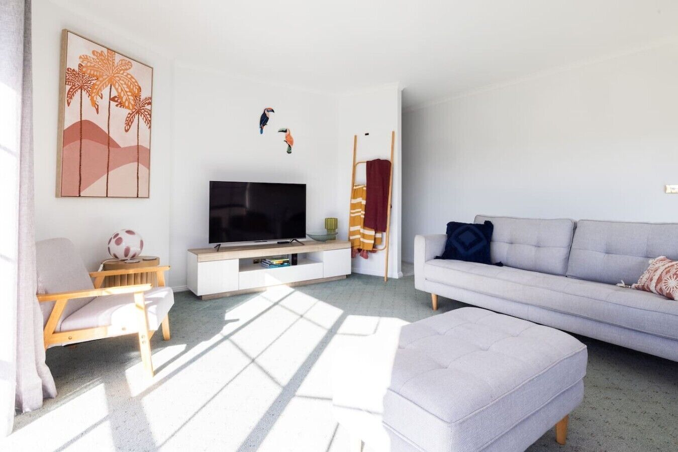 Een moderne woonkamer met een televisie, bank en een schilderij aan de muur.