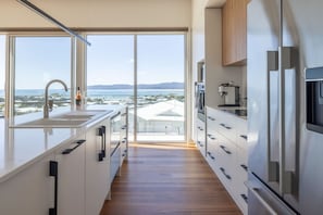 Eine moderne Küche mit großem Fenster und Meerblick sowie Holzboden.