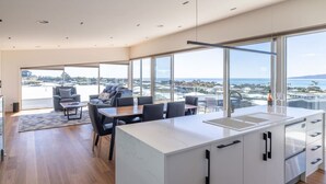 A modern kitchen with a large island, a dining area with a view, and a living space with a sofa and chairs.
