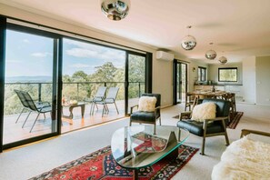 A spacious living area with large windows, a glass coffee table, and a dining area with a view. - Panorama Escape, Port Sorell (Port Sorell)