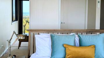 A bedroom with a bed, bedside table, lamp, and a view through an open door.