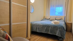 Et hotelværelse med en seng, et natbord, et spejl og et vindue med gardiner.