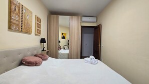 Ein Hotelzimmer mit Bett, Nachttischlampe, Kleiderschrank, Spiegel und Wandbild.