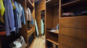 Ein begehbarer Kleiderschrank mit Holzböden, aufgehängter Kleidung und ein paar gefalteten Kleidungsstücken.