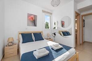 A modern bedroom with a large bed, bedside tables, a window, and a mirror.