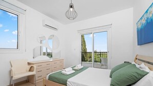 Ein Schlafzimmer mit Bett, Stuhl, Schminktisch und Spiegel, sowie einem Balkon.