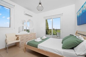 A bedroom with a bed, a chair, a dresser, a mirror, and a balcony.