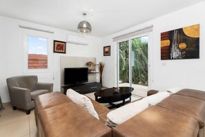 A living room with a sofa set, a television, and a dining table.