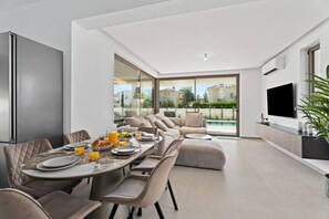 Ein modernes Wohnzimmer mit Essbereich, einem Fernseher und Blick auf einen Swimmingpool.