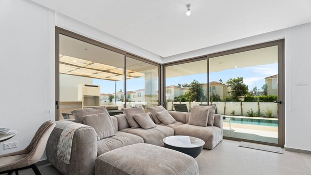 Un salon moderne avec un grand canapé d’angle, une table basse et un coin repas comprenant une table et des chaises.