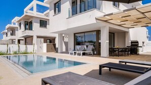 Une villa moderne dotée d’une piscine, d’un espace salon extérieur et d’un coin barbecue.