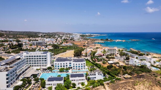 Ein Küstenhotel mit mehreren Swimmingpools, Solaranlagen und Meerblick.