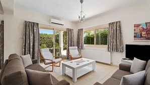 Ein modernes Wohnzimmer mit einer Couch, einem Sessel, einem Couchtisch und einem Fernseher.