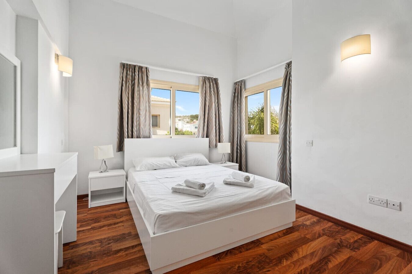 Un dormitorio moderno con una cama grande, mesitas de noche y vistas al exterior.