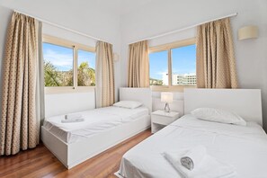A hotel room with two beds, a nightstand, and a window with curtains. - Anthorina Gardens Retreat (Paralimni)