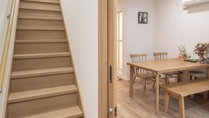 Una scala in legno conduce a una sala da pranzo con tavolo e sedie.
