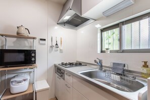 A modern kitchen with a microwave, stove, sink, and various utensils. - shio (Osaka)