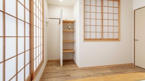 Una stanza con pavimento in legno, una porta scorrevole, una parete bianca e una finestra con inferriate.