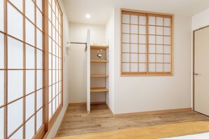 A room with a wooden floor, a sliding door, a white wall, and a window with a grid pattern. - shio (Osaka)