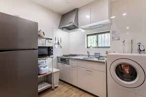 A modern kitchen with a stainless steel refrigerator, microwave, oven, and a built-in washing machine. - shio (Osaka)