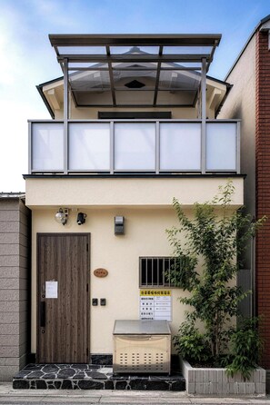 A two-story building with a wooden door, a small outdoor seating area, and a sign with text. - shio (Osaka)
