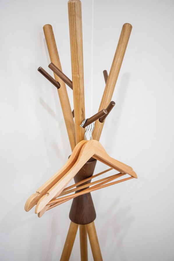 A wooden coat rack with multiple hooks and a wooden hanger. - shio (Osaka)