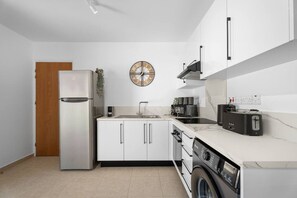 Eine moderne Küche mit einem Edelstahl-Kühlschrank, einer Spüle, einer Kaffeemaschine, einem Toaster und einer Waschmaschine.