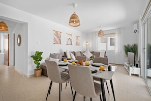 Ein moderner Essbereich mit Tisch für zwei Personen, einer Couch und einem Fernsehschrank.