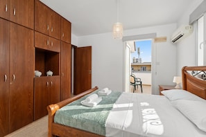 Ein Schlafzimmer mit einem Bett, einem Holzschrank und einem Balkon mit Blick.