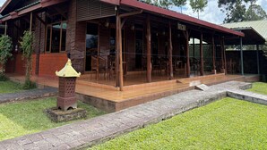 Un edificio de madera con un patio cubierto, mobiliario exterior y un letrero que dice 'BECKY'.
