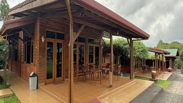 Een houten gebouw met een overdekte patio, grote ramen en een bord waarop 'SISSY' staat.