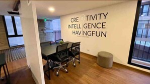 Ein moderner Arbeitsraum mit einem Glastisch, schwarzen Bürostühlen und einem motivierenden Zitat an der Wand.