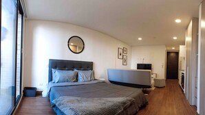 Ein modernes Schlafzimmer mit einem großen Bett, einem runden Spiegel, einem Flachbildfernseher und einem begehbaren Kleiderschrank.