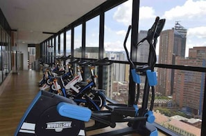 A gym with stationary bikes and treadmills, large windows with a city view. - Modern Studio Apartment (Bogotá)