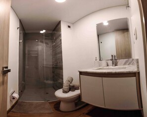 Ein modernes Badezimmer mit Duschkabine aus Glas, Toilette und Waschtisch mit Spiegel.