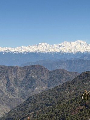 A mountainous landscape with snow-capped peaks and terraced fields. - Hilans Basera 2Km forest walk from road (Kanatal)