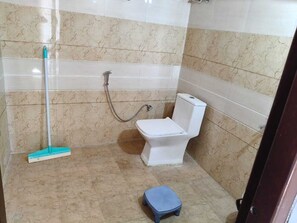 A bathroom with a toilet, a shower, and a mop. - Hilans Basera 2Km forest walk from road (Kanatal)