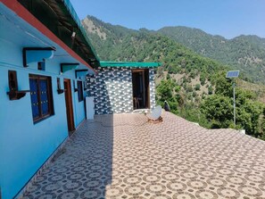 A building with a patterned exterior, a satellite dish, and a mountainous backdrop. - Hilans Basera 2Km forest walk from road (Kanatal)