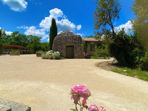 A stone building with a door, surrounded by greenery and a clear sky.