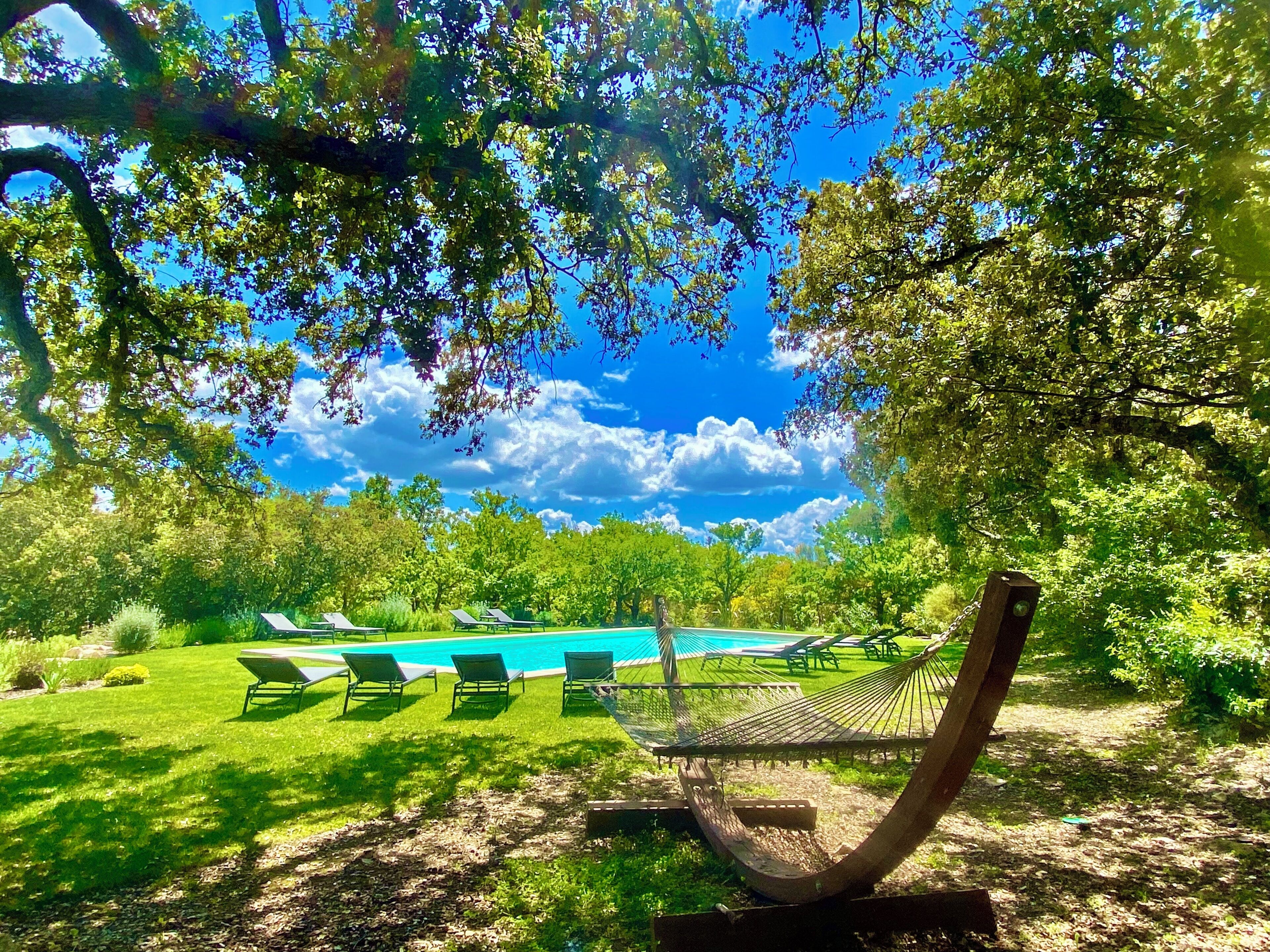 A pool area with lounge chairs and a hammock.