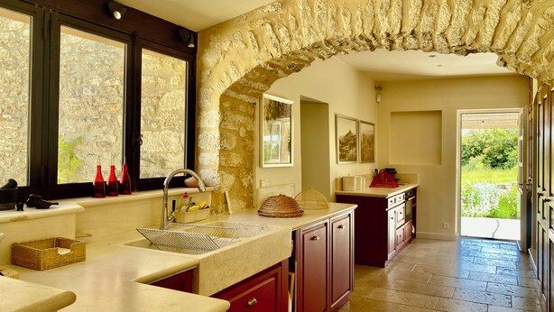 Una cocina con un arco de piedra, una ventana con vistas, y una puerta que da al exterior.