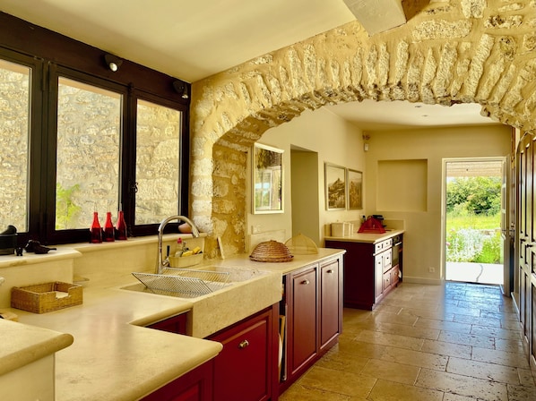 A kitchen with a stone archway, a window with a view, and a door leading outside.