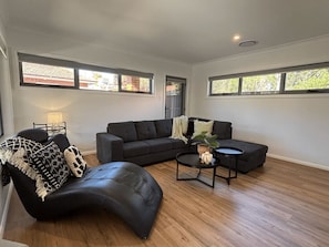A modern living room with a sectional sofa, a curved black leather chair, a small round coffee table, and a lamp.